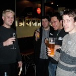 Four people holding drinks and looking at the camera.