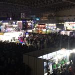A photograph of the showroom floor at the Tokyo Games Show in 2017. Huge crowds of people fill the space and surround the games booths.