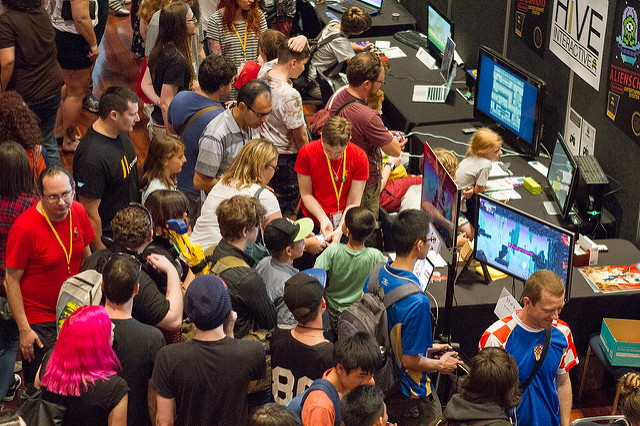 A group of people standing shoulder-to-shoulder, playing games by a local studio