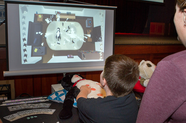 A child plays a game using a large plushi cat as the controller