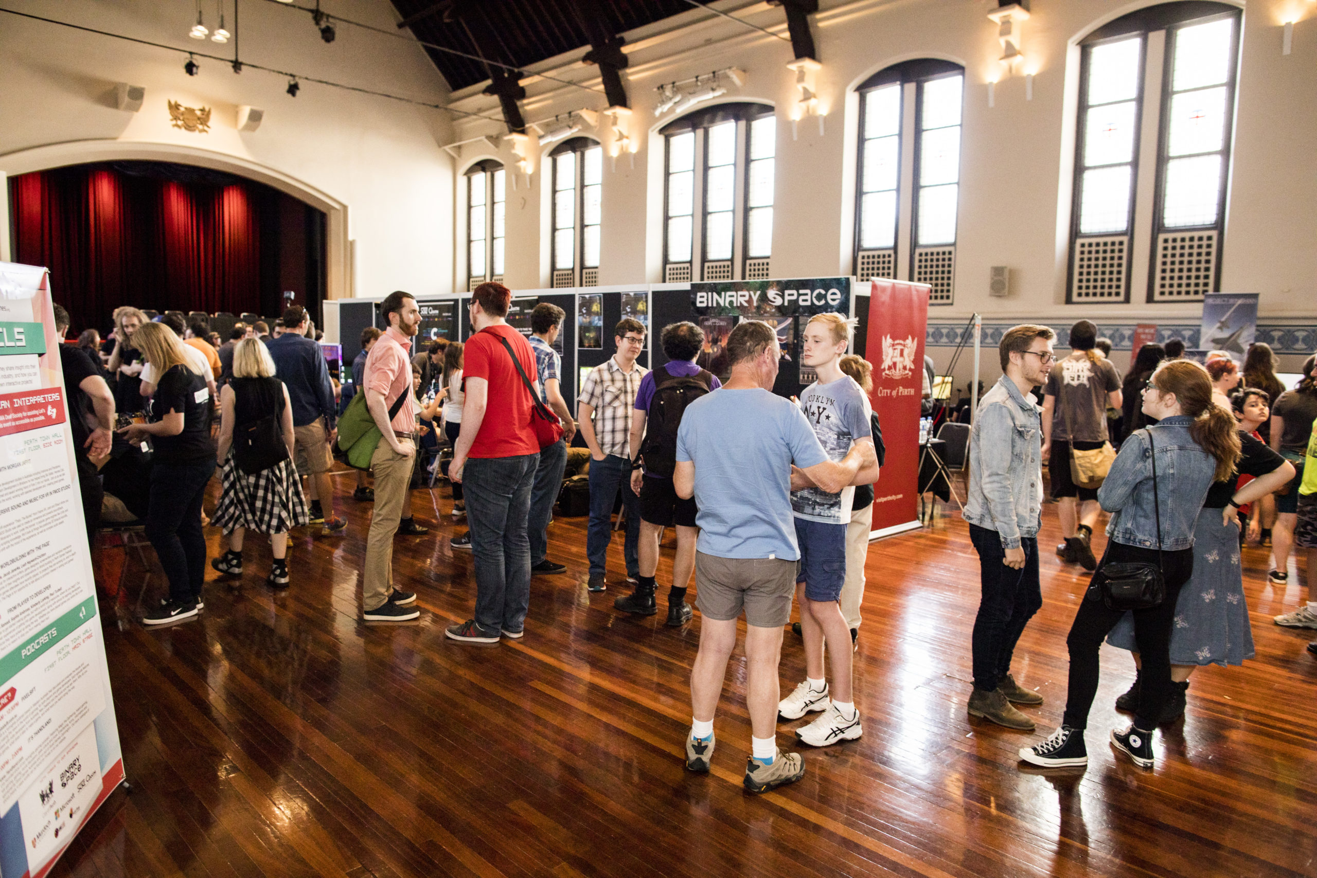 Photo of people standing around game stalls, at a previous Perth Games Festival event in Perth Town Hall